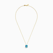 The Ocean Bleu 14K Yellow Gold Blue Topaz Pendant features a square-cut blue topaz wrapped in a diagonal gold band set with small white diamonds, displayed on a plain white background.