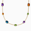 The 14K Yellow Gold Multi-Gemstone Mixed-Shape Station Necklace features seven bezel-set, faceted gemstones in vibrant orange, blue, green, and purple hues, elegantly spaced along the chain.