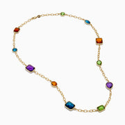 The 14K Yellow Gold Multi-Gemstone Mixed-Shape Station Necklace features seven bezel-set, faceted gemstones in vibrant orange, blue, green, and purple hues, elegantly spaced along the chain.