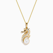 The Novelty 14K Yellow Gold Sea Horse Pendant features white and black diamonds along the body, a round pearl at the tail, and hangs elegantly from a gold chain on a white background.