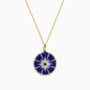 A 14K yellow gold pendant featuring a round blue lapis stone with a white and black diamond compass design—a striking addition to your jewelry collection.