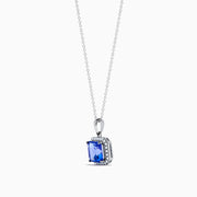 The Nahla Siri 14K Gold Tanzanite and Diamond Pendant features a square blue tanzanite gemstone surrounded by sparkling diamonds, displayed against a white background.