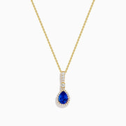 The Nahla 14K Yellow Gold Tanzanite Pendant features a teardrop blue tanzanite surrounded by diamonds and a diamond-accented bail, gleaming at the center of this elegant necklace.