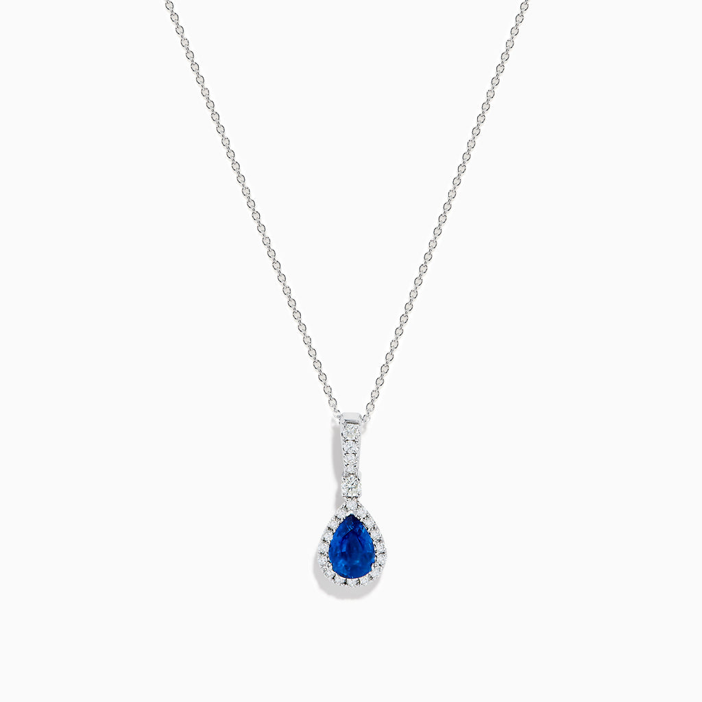 The 14K White Gold Pear Shape Blue Sapphire and Diamond Pendant features a teardrop blue sapphire framed by small clear stones and accented with diamonds set above the main gem.