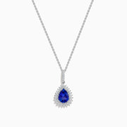 A 14K white gold pear tanzanite and diamond halo pendant with a diamond-studded bail, displayed on a white background.