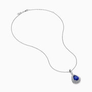 A 14K white gold pear tanzanite and diamond halo pendant with a diamond-studded bail, displayed on a white background.