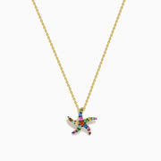 The Seaside 14K Yellow Gold Multi Sapphire Starfish Pendant features a delicate gold chain with a sapphire starfish-shaped pendant adorned with multicolored gemstones, shown elegantly against a white background.