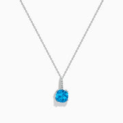 This 14K white gold blue topaz and diamond pendant features a round, vibrant blue topaz and dazzling diamonds set on the bail.