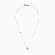 The Lab Grown Blue and White Diamond Halo Necklace in 14K White Gold features a round blue gemstone pendant surrounded by lab grown diamonds, plus two small clear stones set along the chain.