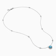 The Lab Grown Blue and White Diamond Halo Necklace in 14K White Gold features a round blue gemstone pendant surrounded by lab grown diamonds, plus two small clear stones set along the chain.