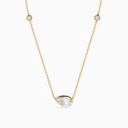 The Lab Grown Diamond Pear Station Necklace in 14K Yellow Gold features a large pear-shaped lab diamond pendant and two small round lab diamonds set along a delicate gold chain.