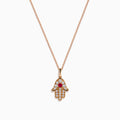 The Ruby Royale 14K Rose Gold Diamond and Ruby Hamsa Pendant features sparkling diamonds and a central ruby, showcased elegantly against a white background.