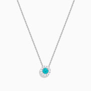 The 18K White Gold Paraiba and Diamond Pendant features a round Paraiba gemstone framed by a halo of white diamonds, elegantly suspended from a fine chain on a white background.