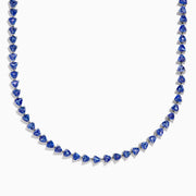 The Nahla Siri Sterling Silver Tanzanite Trillion Cut Tennis Necklace features evenly spaced, triangular tanzanite stones set in 925 silver, creating a continuous, symmetrical design against a plain white background.
