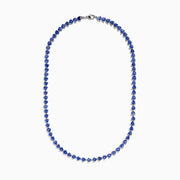 The Nahla Siri Sterling Silver Tanzanite Trillion Cut Tennis Necklace features evenly spaced, triangular tanzanite stones set in 925 silver, creating a continuous, symmetrical design against a plain white background.