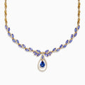 The Nahla Siri 14K Yellow Gold Tanzanite and Diamond Necklace features marquise-cut blue tanzanite gemstones and small diamonds, with a teardrop-shaped tanzanite pendant encircled by a sparkling diamond halo.