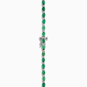 The 925 Sterling Silver Emerald and Diamond Tennis Necklace showcases a sleek row of oval green emeralds and sparkling diamonds set in sterling silver, beautifully arranged against a crisp white background.