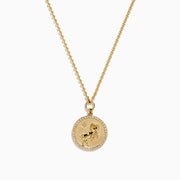 The Zodiac 14K Yellow Gold and Diamond Aries Necklace features a round pendant with an embossed ram, accented by sparkling diamonds, hanging from a delicate gold chain against a white background.