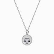 The Zodiac 925 Sterling Silver and Diamond Libra Necklace showcases a round pendant with engraved scales of justice, symbolizing Libra, suspended from a beaded chain.