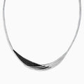 The 14K White Gold Black and White Diamond Necklace features an asymmetrical, sweeping design with textured sections set with small black diamonds.