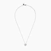 The Lab Grown Heart and Round Diamond Halo Pendant in 14K White Gold features a sparkling heart-shaped lab grown diamond with a halo of smaller diamonds on a delicate silver chain, shown against a plain white background.