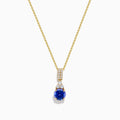 The Nahla 14K Yellow Gold Tanzanite and Diamond Pendant features a round blue tanzanite and white diamonds, set on a yellow gold chain and shown on a white background.