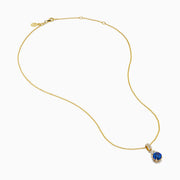 The Nahla 14K Yellow Gold Tanzanite and Diamond Pendant features a round blue tanzanite and white diamonds, set on a yellow gold chain and shown on a white background.