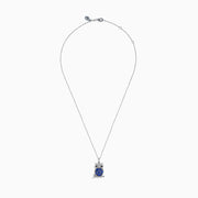 The Nahla 925 Silver Tanzanite and Black Diamond Owl Pendant features black diamond eyes and sparkling tanzanite gemstones on its body, perched on a branch against a white background.
