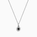 The 14K White Gold Black and White Diamond Halo Pendant showcases an oval black gemstone encircled by sparkling white diamonds, creating a striking contrast against a white background.