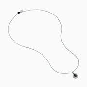 The 14K White Gold Black and White Diamond Halo Pendant showcases an oval black gemstone encircled by sparkling white diamonds, creating a striking contrast against a white background.