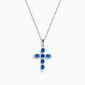 The Royal Bleu 14K White Gold Blue Sapphire Cross Pendant features six oval blue sapphires separated by small clear stones, set on a silver chain and displayed against a white background.