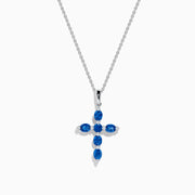 The Royal Bleu 14K White Gold Blue Sapphire Cross Pendant features six oval blue sapphires separated by small clear stones, set on a silver chain and displayed against a white background.
