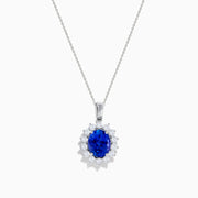 The Nahla Siri 14K White Gold Tanzanite and Diamond Pendant features an oval tanzanite stone encircled by a halo of sparkling diamonds, showcased on a white background.