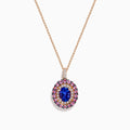The 14K Rose Gold Pink Sapphire, Tanzanite, and Diamond Double Halo Pendant features an oval-shaped blue gemstone surrounded by pink sapphires, tanzanite, and diamonds on a delicate 14K rose gold chain attached at the top.