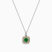 The 14K Two Tone Gold Emerald and Diamond Double Halo Pendant features a central green emerald surrounded by two rows of sparkling diamonds, all suspended from a delicate chain, showcased on a white background.