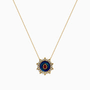 14K Yellow Gold Ruby, Diamond, and Enamel Pendant featuring a delicate gold chain, round pendant with blue and green enamel, a central ruby teardrop, and a sunburst of small clear stones.