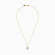 The 18K Yellow Gold Paraiba and Diamond Pendant features an oval turquoise Paraiba gemstone accented by a halo of sparkling diamonds, showcased against a white background.