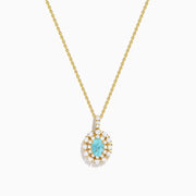 The 18K Yellow Gold Paraiba and Diamond Pendant features an oval turquoise Paraiba gemstone accented by a halo of sparkling diamonds, showcased against a white background.