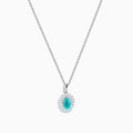 An 18K White Gold Paraiba and Diamond Pendant with an oval Paraiba gemstone and a halo of diamonds hangs from a delicate chain, shown against a plain white background.