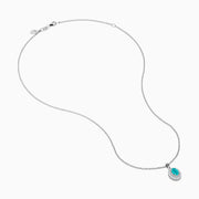 An 18K White Gold Paraiba and Diamond Pendant with an oval Paraiba gemstone and a halo of diamonds hangs from a delicate chain, shown against a plain white background.