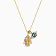 The Novelty 14K Yellow Gold White and Blue Diamond Hamsa & Evil Eye Pendant pairs a diamond Hamsa hand with a blue and white evil eye, both hanging from a delicate yellow gold chain.