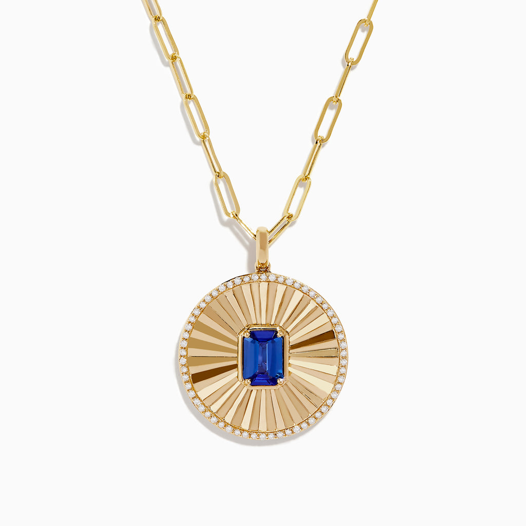 The Nahla Siri 14K Yellow Gold Tanzanite and Diamond Pendant features a round sunburst design with a central blue tanzanite gemstone, accented by diamonds, on an elongated link gold chain.