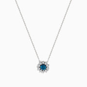The Bella Bleu 14K White Gold Blue and White Diamond Pendant (1.60 TCW) features a flower-shaped design with a central blue stone and sparkling white diamonds, suspended on a fine chain against a plain white background.