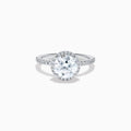 The Star Lab Grown Diamond Halo Ring in 18K White Gold features a large round lab diamond center, encircled by a sparkling halo and delicate stones on the band, shown against a white background.