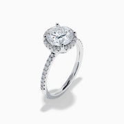 The Star Lab Grown Diamond Halo Ring in 18K White Gold features a large round lab diamond center, encircled by a sparkling halo and delicate stones on the band, shown against a white background.