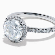 The Star Lab Grown Diamond Halo Ring in 18K White Gold features a large round lab diamond center, encircled by a sparkling halo and delicate stones on the band, shown against a white background.