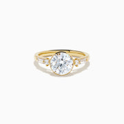 The Star Lab Grown Diamond Moderne Ring in 18K Yellow Gold features a large round lab diamond center, two smaller round diamonds, and baguette-cut side diamonds, shown on a white background.