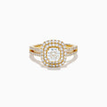 The 18K Yellow Gold Diamond Double Halo Ring showcases a cushion-cut center stone, surrounded by a double halo of round diamonds and additional diamonds set along the split shank band.