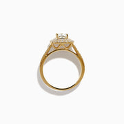 The 18K Yellow Gold Diamond Double Halo Ring showcases a cushion-cut center stone, surrounded by a double halo of round diamonds and additional diamonds set along the split shank band.