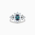 A Platinum GIA Certified Alexandrite and Diamond Starburst Halo Ring, featuring an oval dark blue-green central Alexandrite and sparkling diamond accents, displayed on a white background.